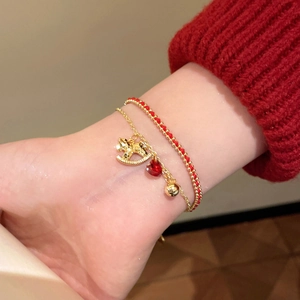 Detail of gold plated pony charm bracelet set with red heart and braided red rope