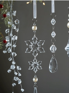 Macro shot of clear acrylic snowflake and teardrop ornaments on a Christmas tree