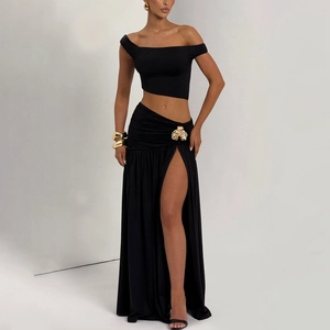 Detail of black two-piece set featuring off-shoulder top and high slit skirt with gold metal