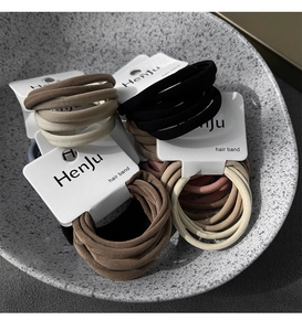 Detail view of elastic fabric hair bands in neutral tones on branded display cards