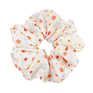 Floral organza scrunchie with orange and yellow patterns on a clean white background