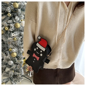 Detail of gingerbread man crossbody bag with gold chain strap on model by Christmas tree