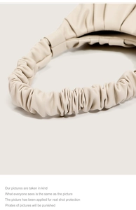 Detailed close-up of cream leather pleated handle on minimalist cloud shoulder bag