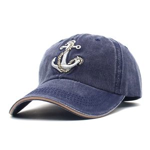 Detailed embroidery of an anchor on a dark blue washed denim baseball cap with brown stitching