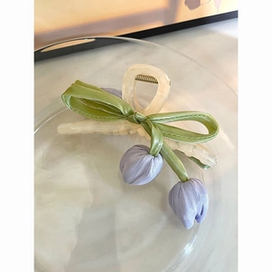 Detailed shot of cream tulip hair claw clip with purple fabric flowers and green bow