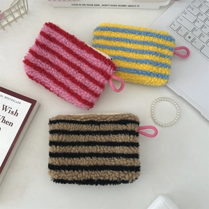 Close-up of striped plush heart pouches in various colors on a modern white desk