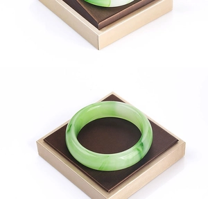Detailed view of emerald green jade-like bracelets with smooth texture on white background