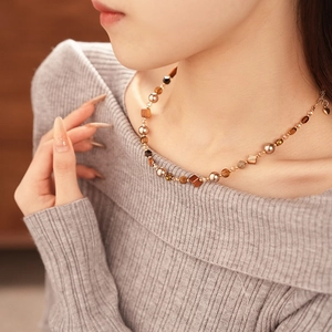 Detail of beaded necklace with faux tiger eye stones and a gold heart pendant charm