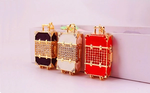 Detailed view of three mini suitcase keychains in black, white and red with shiny rhinestones