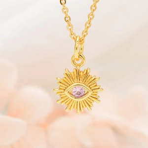 Macro detail of golden sunflower necklace with pink zircon evil eye stone pendant