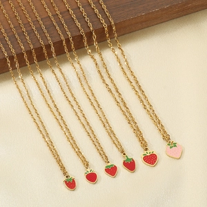 Close-up of golden twisted chain necklaces featuring red and pink strawberry pendants