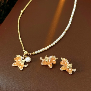 Detailed set of gold unicorn necklace and earrings with orange crystal and pearls