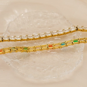 Nahaufnahme goldener Tennisarmbänder mit bunten Zirkonia auf Eisglas-Textur