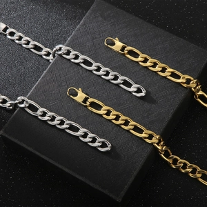 Close-up of gold and silver stainless steel Figaro link chains on textured background
