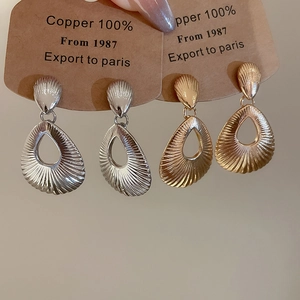 Close-up of textured teardrop earrings in gold and silver finish made of 100% copper