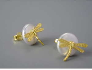 Macro shot of S925 silver dragonfly earrings with white pearls and gold-plated details