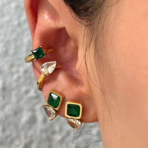 Close-up of vintage gold ear cuff and stud set with emerald zircon and pear-cut stone