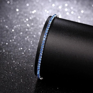 Detailed view of single row blue crystal tennis bracelet on black luxury display stand