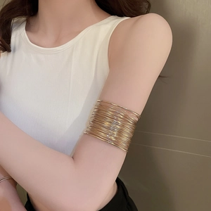 Chic gold multi-layer hollow arm cuff bracelet on upper arm with minimalist metallic finish
