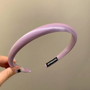 Detail of purple padded satin headband showing silky texture and handmade inner label