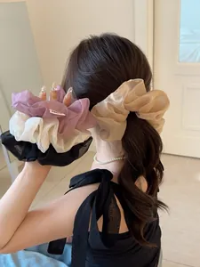 Dettaglio di elastici in organza trasparente nei colori viola, beige, bianco e nero