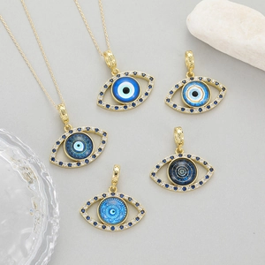 Gold Evil Eye pendants with blue crystal accents on stone and cement backgrounds