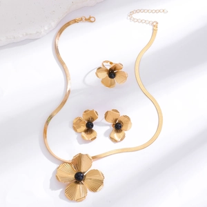 Detailed view of golden flower jewelry set with black beads and sunburst texture