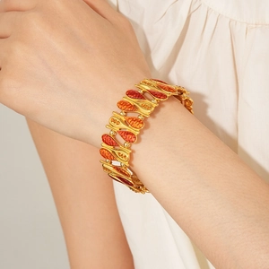 Detail of vintage gold leaf bracelet with orange enamel and sparkling zircon crystals