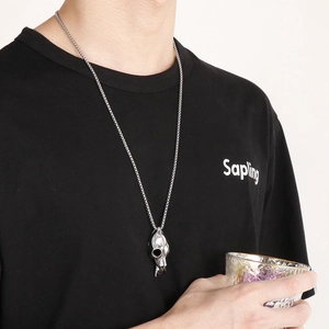 Detail of a vintage silver skull pendant on a long chain worn by a male model