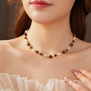 Close-up of vintage tiger eye and pearl necklace worn on model for elegant style