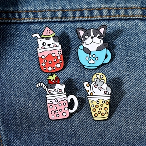 Set of four cute cartoon cat enamel pins in colorful beverage cups on blue denim fabric
