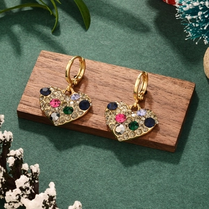Gros plan de boucles d'oreilles cœur dorées avec strass colorés sur décor festif