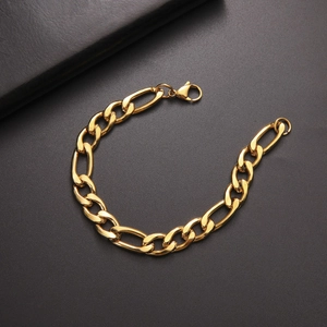 Detail of gold-plated Figaro chain bracelet with sturdy lobster clasp on textured surface
