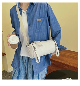 Quilted white barrel crossbody bag with adjustable strap shown on a female model