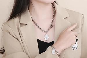 Close-up of silver Hamsa Hand pendant on a chunky chain necklace and bracelet jewelry set
