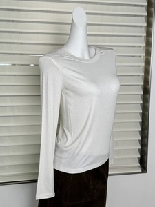 Detail view of white long-sleeved wool T-shirt on mannequin showing slim fit and round neck