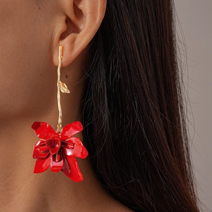 Detail of red floral earrings with long gold hooks worn by a model in a close-up profile
