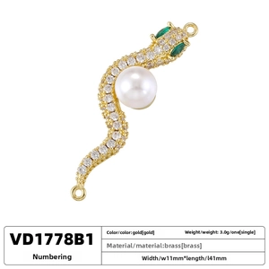 Detailed view of brass snake pendant with inlaid pearls and green gemstone eyes