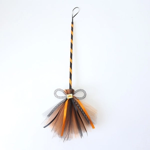 Detail of Halloween witch broom with orange and black mesh bristles and grey ribbon bow