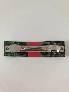 Close-up of a miniature book hair clip with colorful covers on a silver metal base