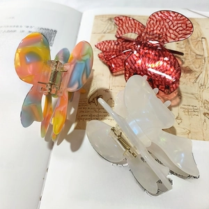 Three elegant French lace bow hair clips in marble, red plaid, and pearl white on a book