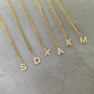 Macro detail of gold initial pendants S, D, X, A, K, M with sparkling diamond pave setting