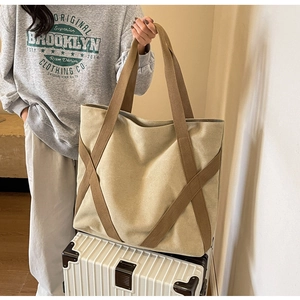 Detail of canvas tote bag with brown straps placed on a white suitcase for travel