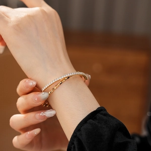 Detail of double-layer gold bracelet with zircon stones on a female wrist