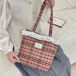 Close-up of vintage wool plaid tote bag with delicate lace trim and happy embroidery