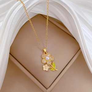 Detail of gold flower necklace with white pearl, sparkling crystals and green enamel leaves