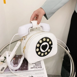 Close-up of creative white patent leather shoulder bag in vintage rotary telephone design