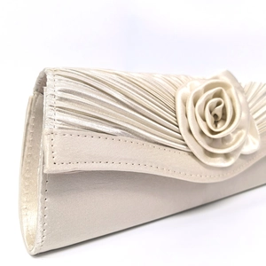 Detail of cream white satin clutch bag with 3D rose decoration and pleated texture