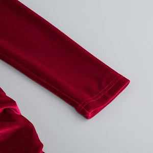Détail des poignets à double couture sur une robe en velours rouge profond