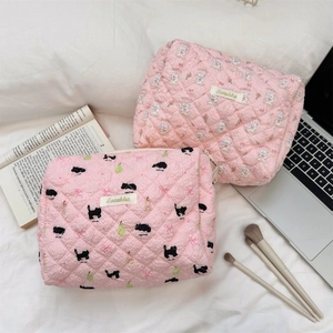 Close-up of pink quilted makeup bags with rabbit and cat patterns on white bedding